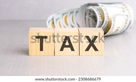 word TAX on wooden cubes, grey background, business concept