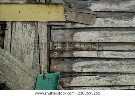 Detail of and old humble hut wall made with recycled wooden planks with worn out paint