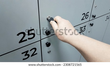 A man's hand opens the door of a locker for storing personal items in a public locker room with a key. Furniture for a sports complex or enterprise. Thirso-plate product Royalty-Free Stock Photo #2308721565