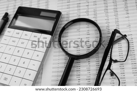 Calculator, magnifying glass, pen, eye glasses on financial statement.