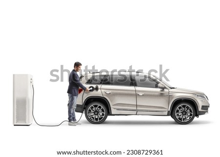 Full length shot of a man charging a SUV from an electric  vehicle station isolated on white background Royalty-Free Stock Photo #2308729361