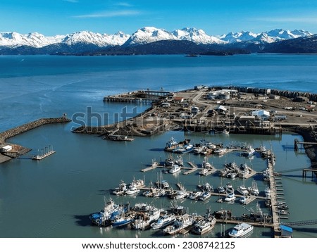 aerial view of homer alaska marina and chugach mountains along cook inlet on sunny, blue sky winter day