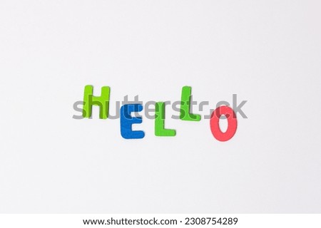 The word hello made of colored wooden letters on a light gray background. Blue and red letters form the greeting word hello.
