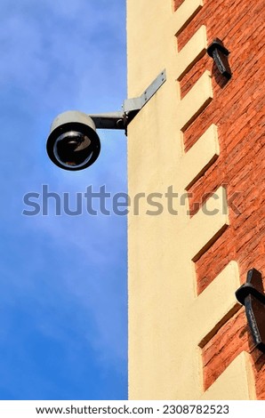 Municipal monitoring on the wall of the tenement house. Security camera on building against a blue sky background.