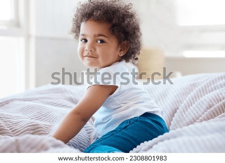 Happy portrait, girl and kid in bedroom for fun, childhood development and baby growth with curly hair. Cute, adorable and sweet toddler, young child or relaxing on comfortable bed in nursery at home Royalty-Free Stock Photo #2308801983