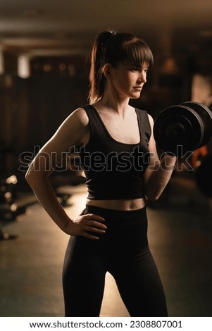 Caucasian woman doing biceps workouts using dumbbell exercise at gym for good healthy in fitness. Lifestyle and sport exercise concept. Royalty-Free Stock Photo #2308807001