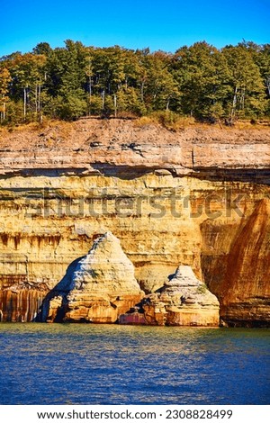 National Park Pictured Rocks collapsed cliff wall jutting out of indigo lake water with forest above