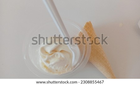 white ice cream in a clear plastic cup and a cone-shaped brown biscuit container that has a delicious taste