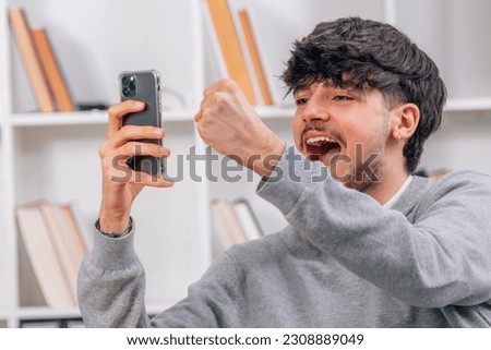 excited student celebrating looking at mobile phone