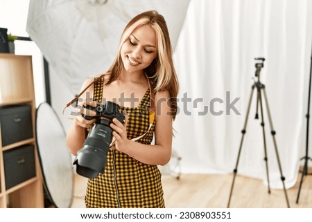 Young caucasian woman photographer holding professional camera photo studio