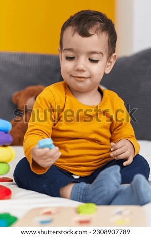 Adorable hispanic boy playing with maths puzzle game sitting on bed at bedroom