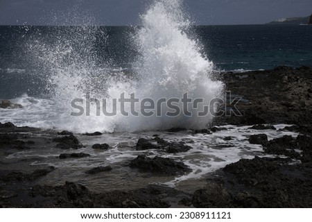 Gran Canaria, north west coast around natural swimming pools Salinas de Agaete, 
waves breaking against old eroded dark lava platform Royalty-Free Stock Photo #2308911121