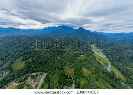 Mesmerizing aerial photo of Crocker Range, Sabah, Malaysia. Stunning Mount Kinabalu with lenticular cloud, rivers, villages, and captivating leading lines. Tranquil overcast day beauty.