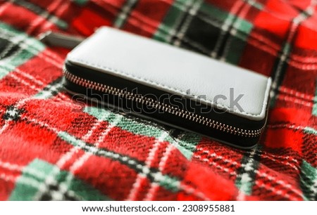 Purple leather wallet on checkered plaid background.