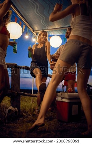 Young people celebrating, dancing and having fun outdoors in camp. Summertime sunset. Travel, weekend, togetherness, lifestyle concept. Royalty-Free Stock Photo #2308963061