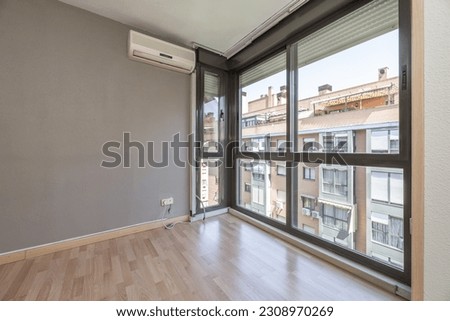 Corner of a room with sliding aluminum windows, air conditioner unit hanging on the wall