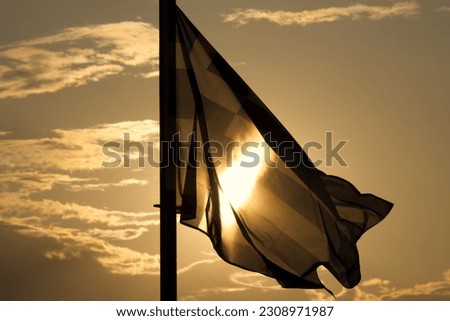 Silhouette of Greek flag against sunset sky, end or beginning of holidays in Greece concept. 