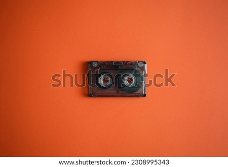 Audio cassette in the middle on an orange background, top view.