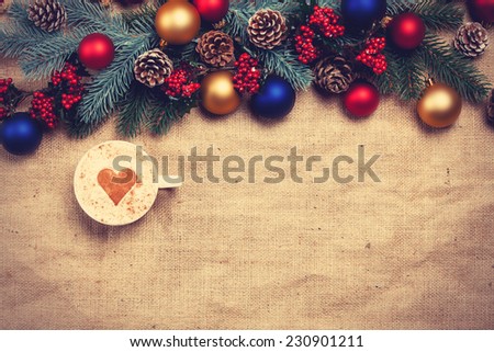Hot cappuccino with christmas tree shape on a table near pine branches