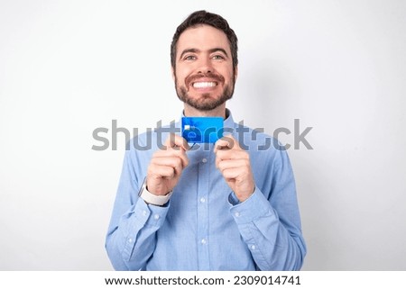 Photo of handsome businessman wearing blue shirt over white studio background positive smile hold credit card income salary