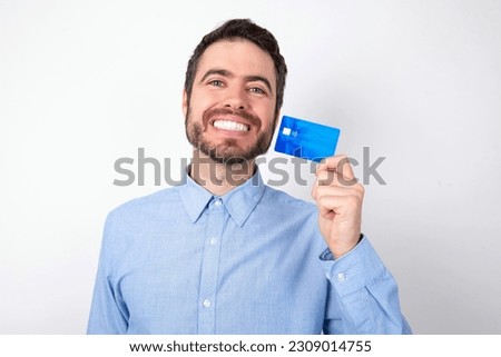 Close up photo of optimistic handsome businessman wearing blue shirt over white studio background hold card