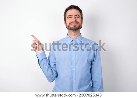handsome businessman wearing blue shirt over white studio background  points to side on blank space demonstrates advertisement. People and promotion concept