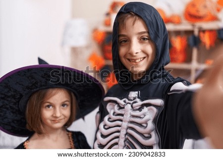 Adorable boy and girl wearing halloween costume make selfie by camera at home