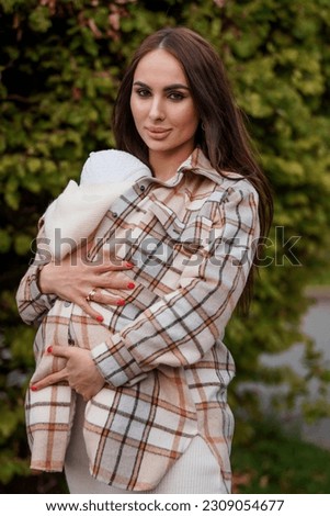 A beautiful girl is holding a baby in her arms. Mother holding baby in her arms