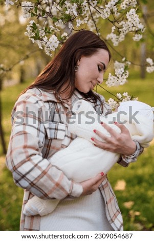 A beautiful girl is holding a baby in her arms. Mother holding baby in her arms