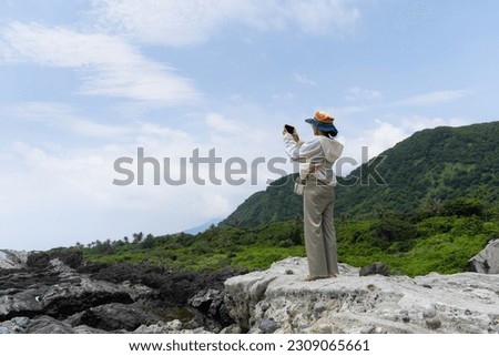 Hiking woman use cellphone to take photo and stand beside the beach
