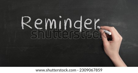 A woman's hand write text reminder with chalk on chalkboard