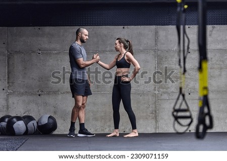 Muscular man and fit woman in a conversation before commencing their training session in a modern gym. Royalty-Free Stock Photo #2309071159