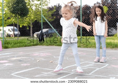 Two little girls playing hopscotch, We love to play together