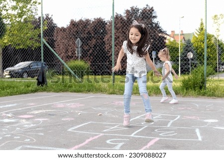 Two little girls playing hopscotch, We love to play together