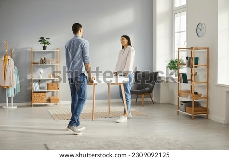 Joyful young family couple moving furniture at home. Happy husband and wife carrying a table together. Cheerful man and woman buy a new desk and put it in the living room in their new house Royalty-Free Stock Photo #2309092125