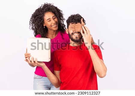 Playful couple covering eyes on white background. Girlfriend covering boyfriend's eyes to make surprise. Valentine's Day