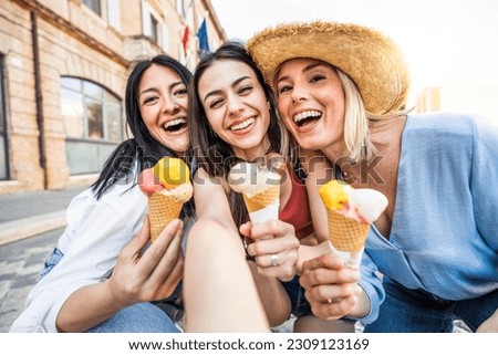 Three cheerful teenage women eating ice cream cones on city street - Happy female tourists enjoying summer vacation in Italy - Laughing girl friends taking selfie picture outside - Summertime holidays