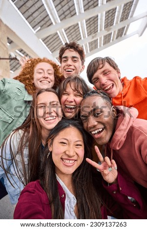 Vertical multi-ethnic group smiling student boys and girls taking selfie outdoors. Happy lifestyle concept of friendship in multicultural young people having fun day together. Seven partners enjoying.