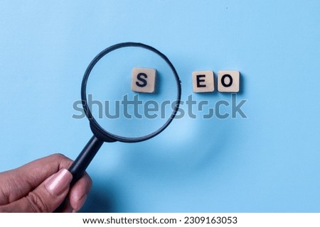 Magnifying glass focus on S letter of SEO word, Search Engine Optimization on a blue background.