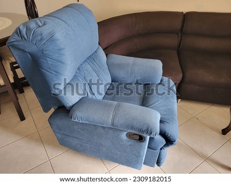 Blue recliner chair in the living room with a black couch and a dinning table behind Royalty-Free Stock Photo #2309182015