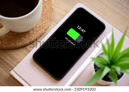 Phone with charged battery on the screen background of wooden table in the office Royalty-Free Stock Photo #2309193203