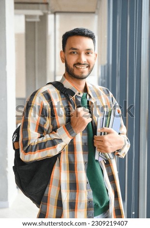 Handsome young Indian boy student with books and backpack at university. Education concept.