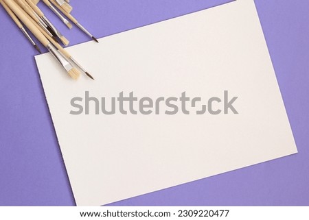 empty white paper page on purple background with aquarelle brushes
