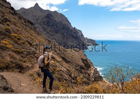 Backpack woman on hiking trail from Afur to Taganana with scenic view of Atlantic Ocean coastline and Anaga mountain range, Tenerife, Canary Islands, Spain, Europe. Looking at Cabezo el Tablero crag Royalty-Free Stock Photo #2309229811