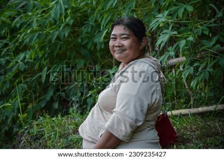Close Up A Woman Sits And Smiles Among The Cassava Plants In The Agricultural Area At The Village
