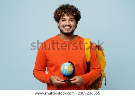 Young teen Indian boy geography student wears casual clothes backpack bag hold in hands Earth world globe isolated on plain pastel light blue cyan background. High school university college concept Royalty-Free Stock Photo #2309236555