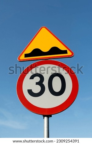 Colored road signs against the blue sky mean that the road is unpaved and the driver is obliged to reduce speed