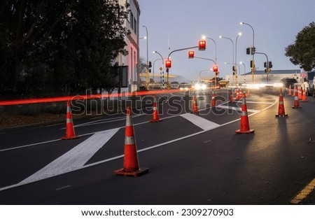 Orange traffic cones lined up on the road. Car light trails on the road intersection. Auckland.  Royalty-Free Stock Photo #2309270903
