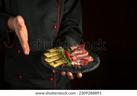 Professional chef presents a sliced steak with beef and cheese on a serving plate. The concept of serving dishes to order by a waiter with space for advertising on a dark background