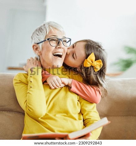 Portrait of grandmother and granddaughter having fun together reading a book at home